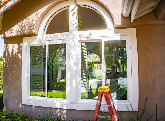 Arched white replacement windows Laguna Niguel, CA installed on a stucco home exterior.