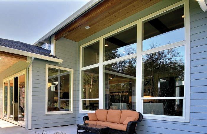 Modern coastal home exterior with large floor-to-ceiling windows and patio seating, showcasing stylish Laguna Beach, CA replacement windows that enhance natural light, ocean views, and energy efficiency.