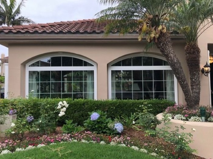 large arched grid-style windows with white frames on a landscaped home exterior showcasing lake forest, ca replacement windows