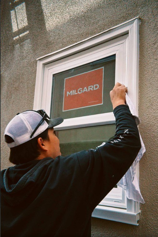 Installer cleaning a newly installed Milgard window on a stucco home exterior for Lake Forest, CA replacement windows